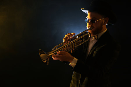Professional musician playing trumpet on black background. Space for textの写真素材