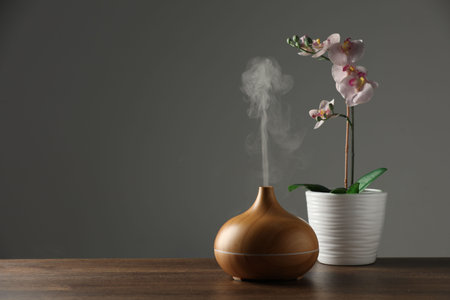 Aroma oil diffuser and orchid flower on wooden table, space for textの写真素材