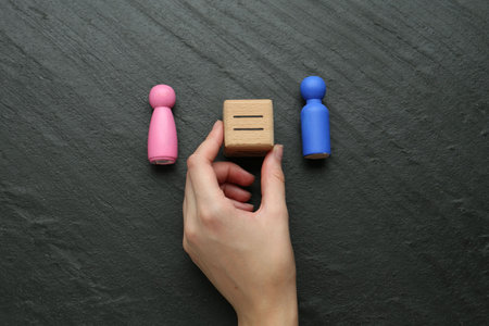 Gender equality concept. Woman holding wooden cube with equals sign between female and male figures...