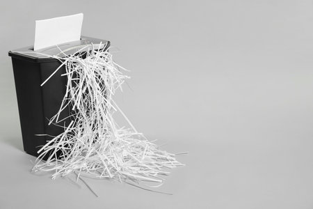 Destroying sheet of paper with shredder on light grey background, space for textの写真素材