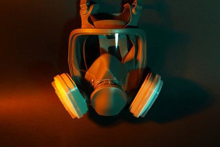 One respirator mask on dark background in orange light. Safety equipmentの写真素材
