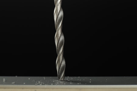Drilling hole in gray surface on black background, closeup. Space for text