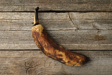 Overripe banana with dark spots on wooden table, top viewの写真素材