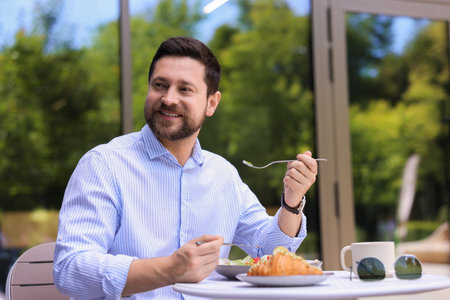 Happy man having breakfast in outdoor cafeの写真素材