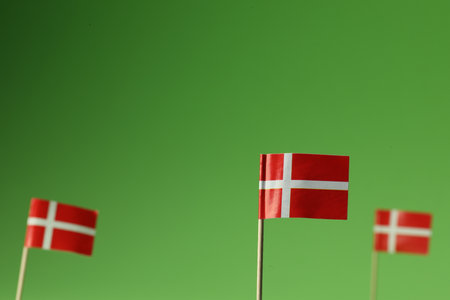 Small paper flags of Denmark on green background, selective focus. Space for textの写真素材