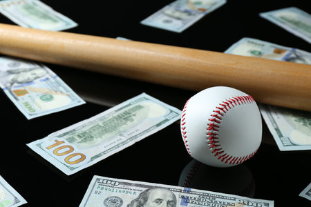 Baseball ball, bat and dollar banknotes on black backgroundの写真素材