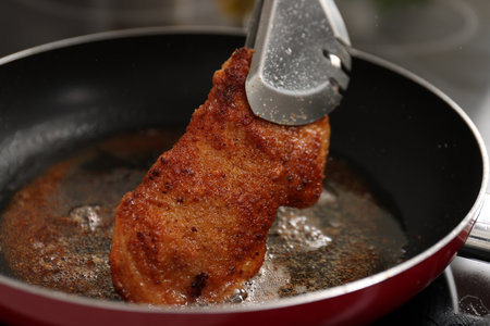 Cooking schnitzel in frying pan on stove, closeupの写真素材