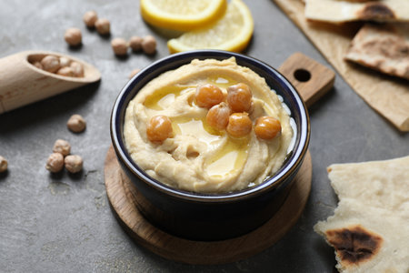 Delicious hummus with olive oil and chickpeas in bowl on grey tableの写真素材