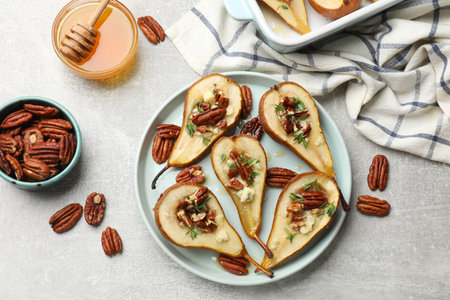 Tasty baked pears with nuts, blue cheese, thyme and honey on light grey table, flat layの写真素材