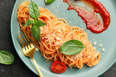 Delicious pasta with tomato sauce, basil and cheese served on black table, top viewの写真素材