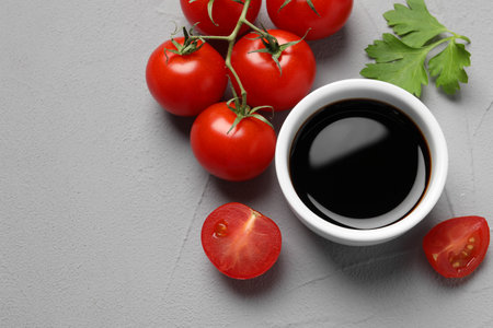 Balsamic vinegar, tomatoes and parsley on light gray textured table, flat lay. Space for textの写真素材