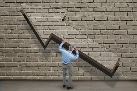 Small man holding big arrow near brick wall. Concepts of success, aiming, balancingの写真素材