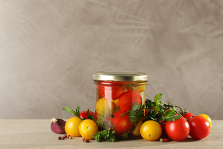 Different pickled tomatoes in jar and fresh ingredients on wooden tableの写真素材