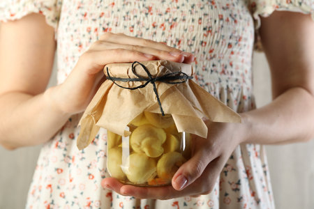Woman with jar of tasty pickled mushrooms on light background, closeupの写真素材