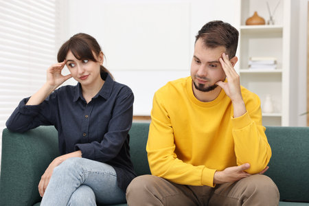 Embarrassed couple ignoring each other on sofa at homeの写真素材