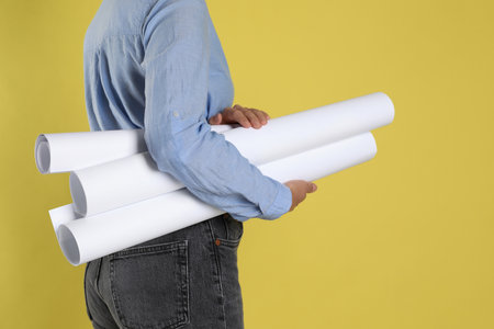 Engineer with drafts on yellow background, closeup