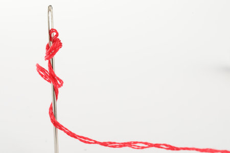 Sewing needle with red thread isolated on white, closeup