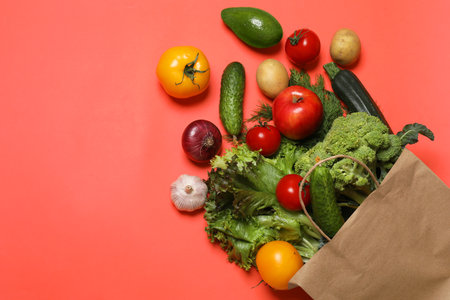 Delivery of vegetarian products. Bag with different vegetables and fruits on red background, top viewの写真素材