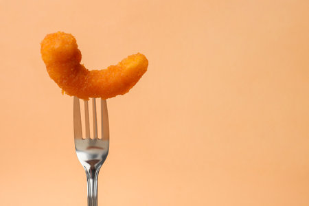 Fork with tasty fried shrimp on pale orange background, closeup. Space for textの写真素材