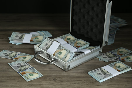 Metal case with dollar banknotes on wooden tableの写真素材