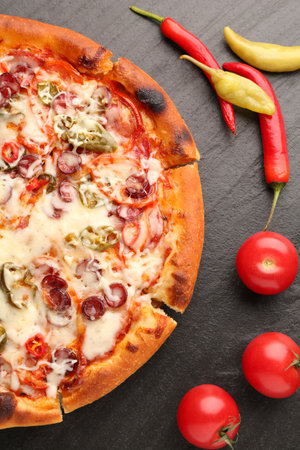 Delicious pizza Diablo, tomatoes and peppers on dark textured table, flat layの写真素材