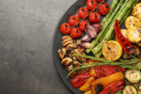 Delicious grilled vegetables on grey textured table, top view. Space for textの写真素材
