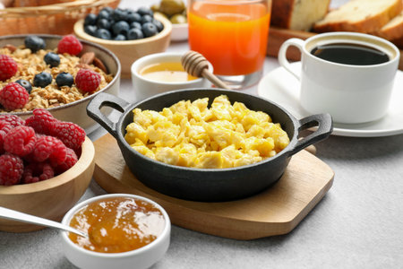 Tasty breakfast. Scrambled eggs, coffee, jam and other food on grey textured table, closeupの写真素材
