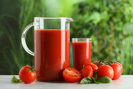 Tasty tomato juice, basil and fresh vegetables on white table outdoorsの写真素材