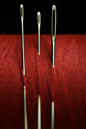 Spool of red sewing thread with needles on black background, macro viewの写真素材