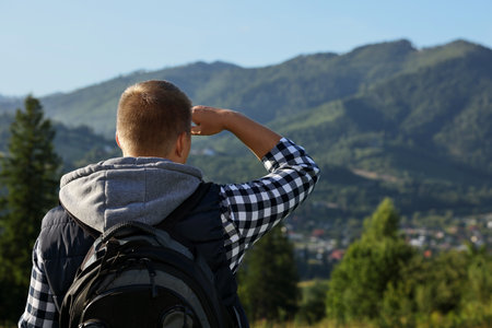 Man with backpack in beautiful mountains, back view. Space for textの写真素材