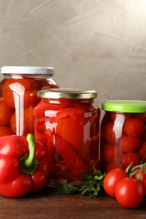 Different pickled vegetables in jars and fresh ingredients on wooden tableの写真素材