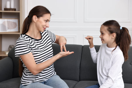 Woman and her daughter using sign language for communication at homeの写真素材