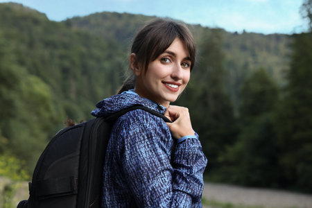 Smiling woman with backpack in beautiful mountainsの写真素材