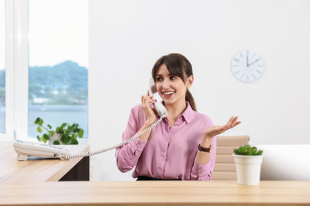 Portrait of receptionist at wooden desk in officeの写真素材
