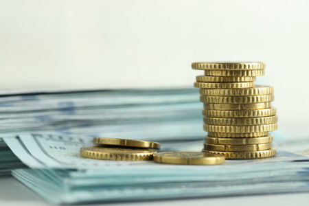 Stack of euro coins and dollar banknotes on white background, closeup