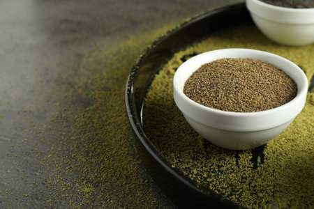 Superfood powder in bowl on grey table, closeup. Space for text