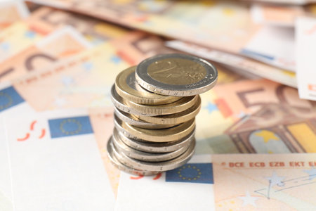 Stack of coins on euro banknotes, closeup