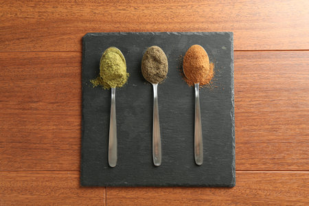 Different superfood powders in spoons on wooden table, top viewの写真素材