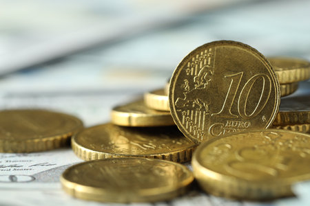 Many euro coins on dollar banknotes, closeup