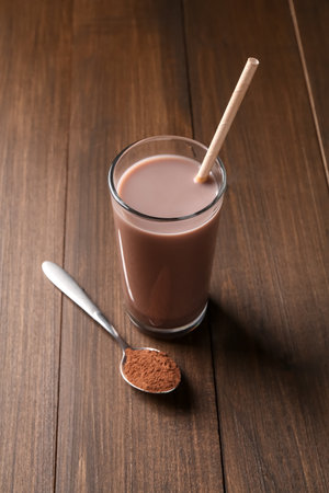 Delicious protein shake in glass and spoon with powder on wooden tableの写真素材