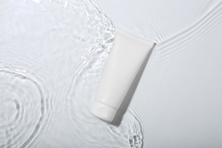 Cosmetic product. Tube with cream in water on light background, top viewの写真素材