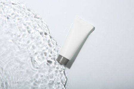 Cosmetic product. Tube with cream in water on light background, top viewの写真素材