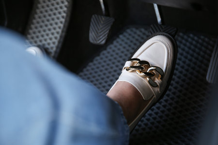 Woman in white shoes pushing on pedal of car brake, closeupの写真素材