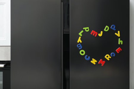 Heart made of many bright magnetic letters on refrigerator indoors. Learning alphabetの写真素材