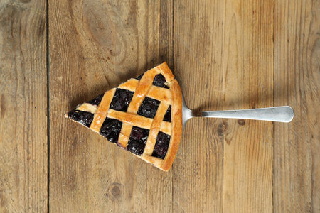 Piece of tasty homemade blueberry pie and server on wooden table, top viewの写真素材