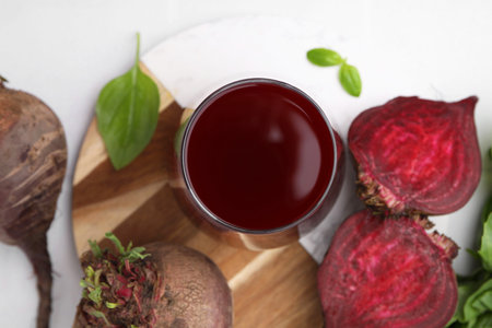 Fresh beet juice in glass and ripe vegetables on white table, flat layの写真素材