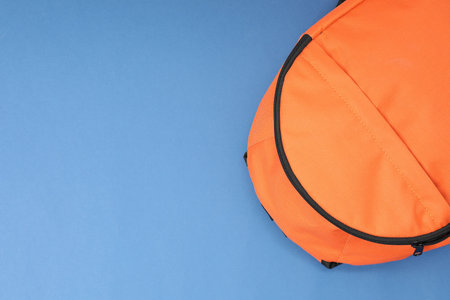 Orange backpack on blue background, top view. Space for text