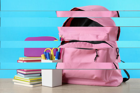 Backpack with different school stationery on wooden table against light blue background