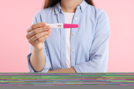 Woman holding pregnancy test on pink background, closeupの写真素材