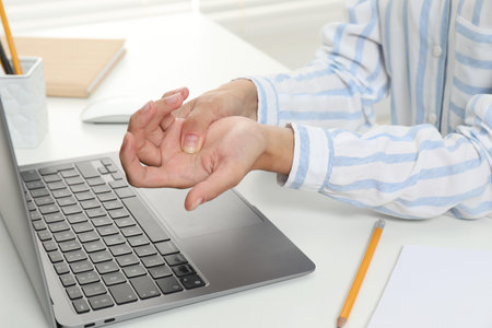 Carpal tunnel syndrome. Woman suffering from pain in wrist at desk, closeupの写真素材